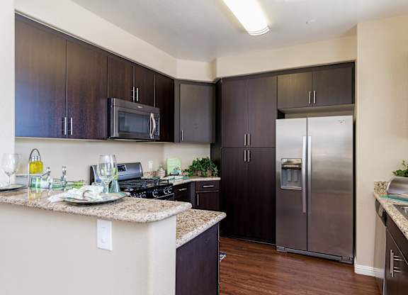 A kitchen with dark brown cabinets and a granite counter top.