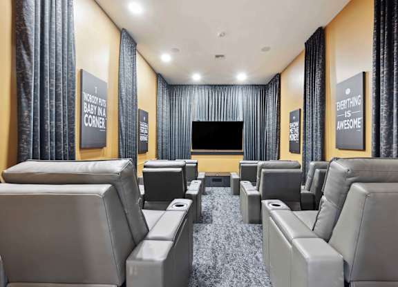 A home theater with grey seats and a black screen.