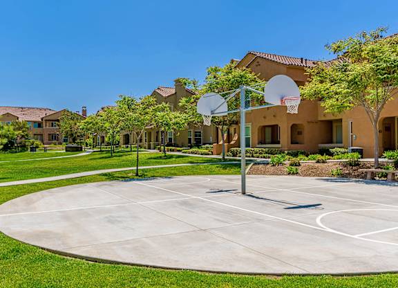 A basketball court is surrounded by houses and trees.