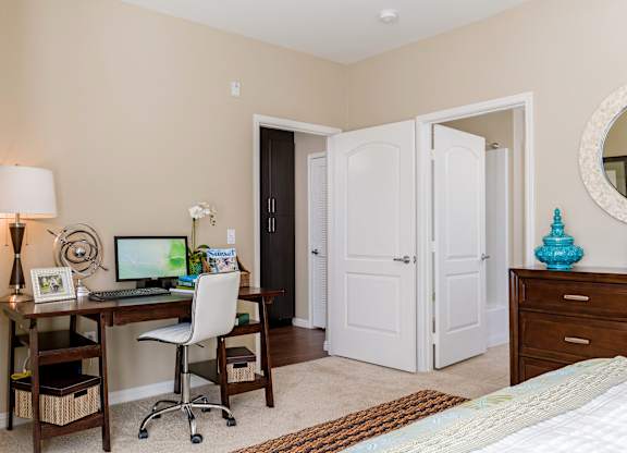 A room with a desk, chair, and bed.