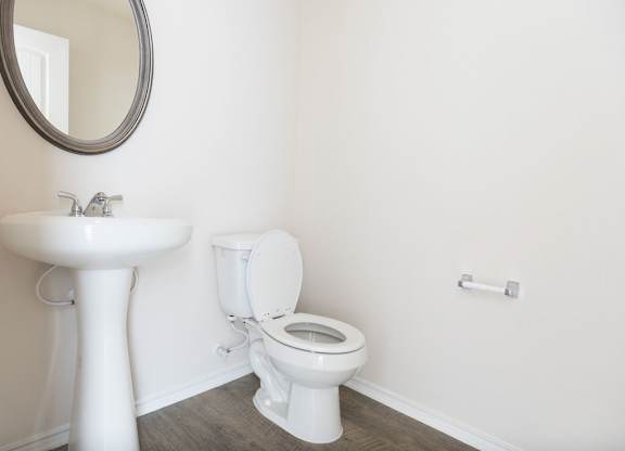 A white toilet sits next to a white pedestal sink in a bathroom.