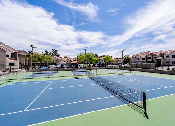 A tennis court with a blue surface and a green border.
