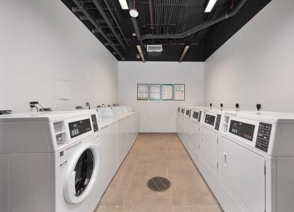 a laundry room with washers and dryers and a row of washing machines