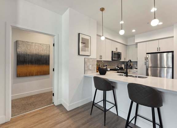 A kitchen with a white counter and bar stools.