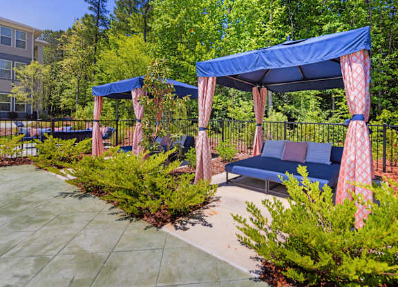 A blue canopy with red curtains is over a bench.