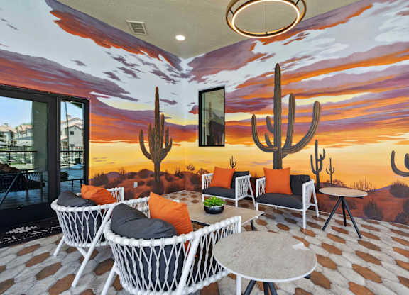A room with a desert mural on the wall and a table with chairs in front of it.