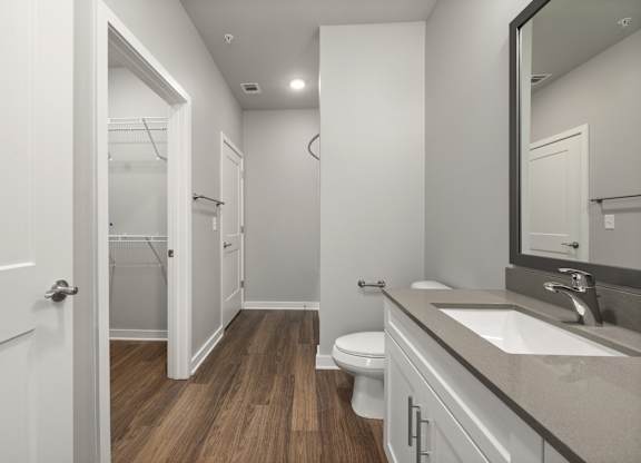 A bathroom with a toilet, sink, and mirror.