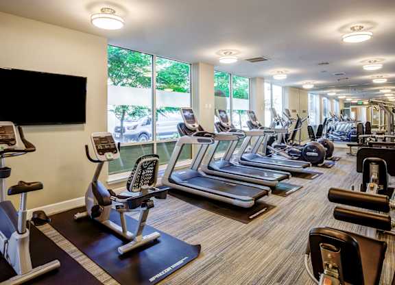 A gym with a variety of equipment including treadmills, stationary bikes, and weight machines.