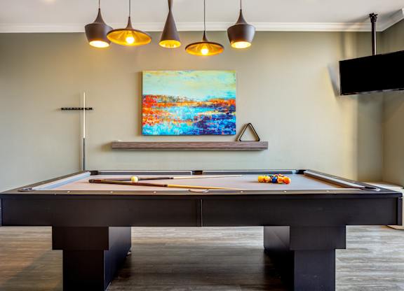 A pool table with a painting hanging above it.