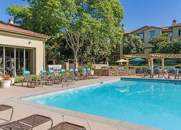 A large swimming pool surrounded by lounge chairs and trees.