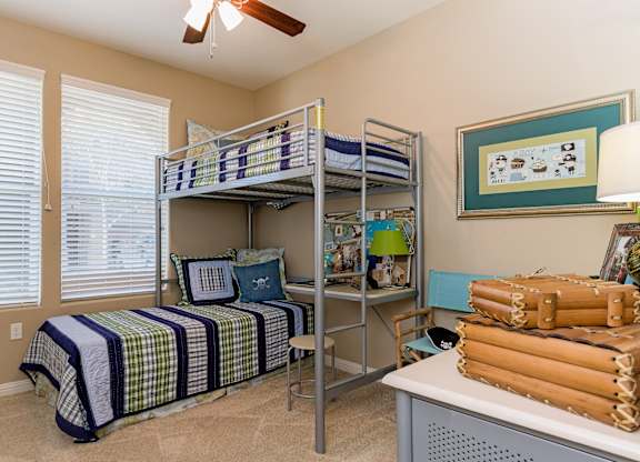 A room with a bed, a desk, and a fan.