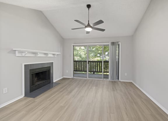 an empty living room with a fireplace and a ceiling fan