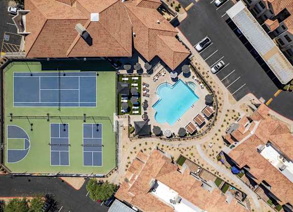 A tennis court with a pool and a building in the background.