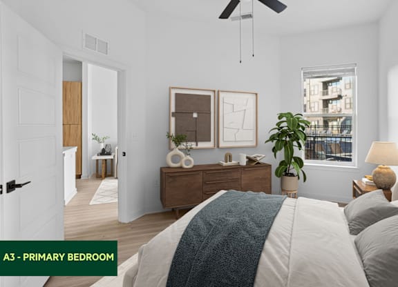 A bedroom with a bed, nightstand, and a plant.