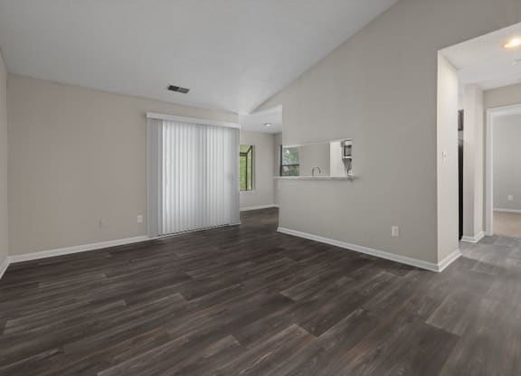 the living room and kitchen of a new home with white walls and wood flooring