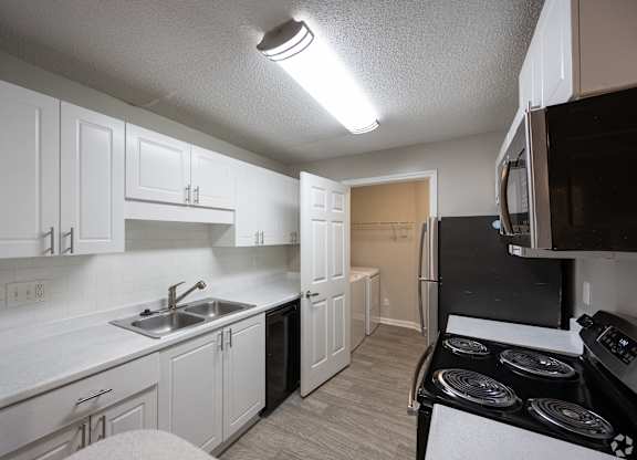 A kitchen with white cabinets and a black stove top.