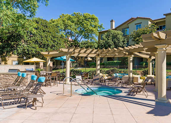A pool area with sun loungers and a pergola.