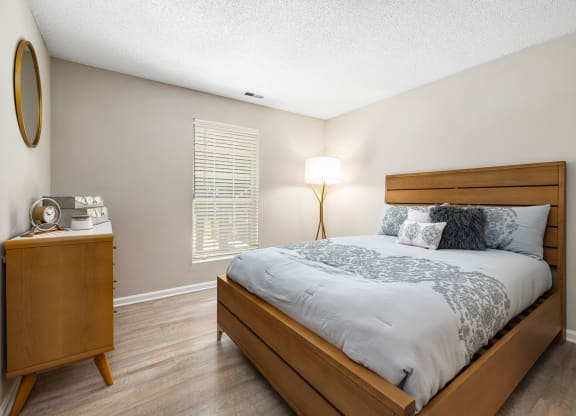 a bedroom with a bed and a dresser with a lamp at View at Lake Lynn, North Carolina, 27613