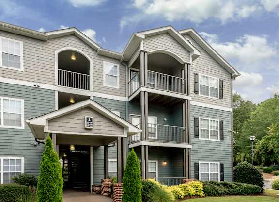 A grey two-story apartment building with a balcony on the second floor.
