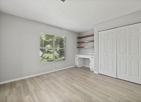 an empty living room with white doors and a window