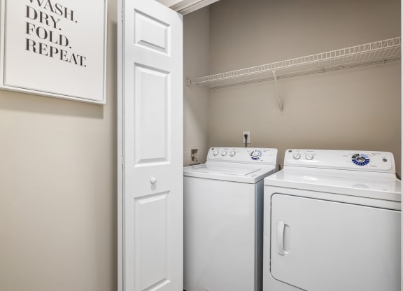 an empty laundry room with two white washers and dryers and a white door at Mariners Crossing, Raleigh