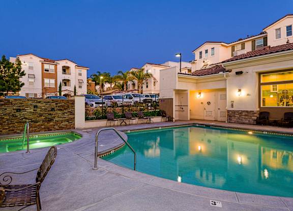 A swimming pool surrounded by chairs and a stone wall.