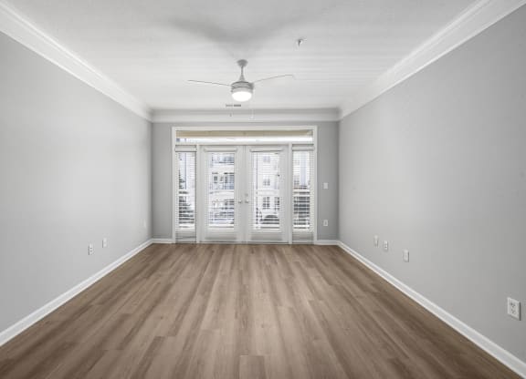 an empty living room with hardwood floors and a ceiling fan