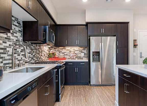 Kitchen with stainless steel appliances and wooden cabinets at Altura, San Diego