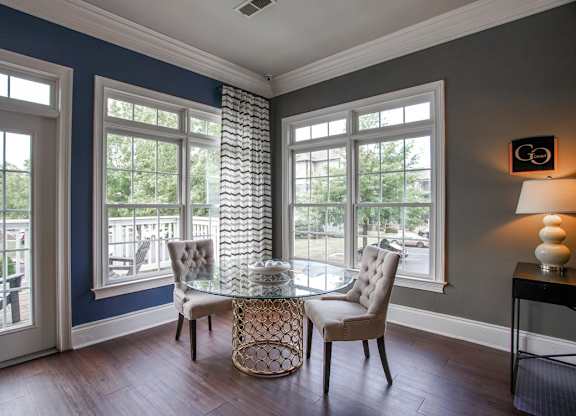 A room with a table and chairs in front of a window.