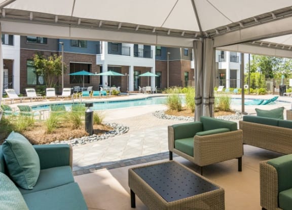 a lobby with couches and chairs and a pool with umbrellas