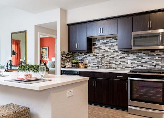 Kitchen with stainless steel appliances and wooden cabinets at Altura, San Diego