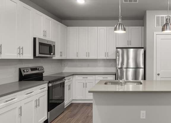 A modern kitchen with white cabinets and stainless steel appliances.
