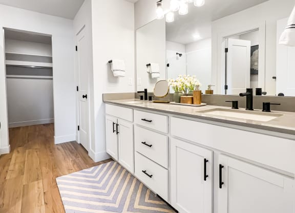 a bathroom with white cabinets and a striped rug