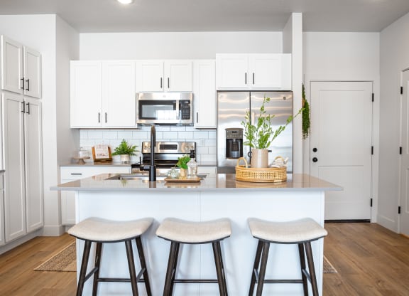 a kitchen with white cabinets and a large island with three stools