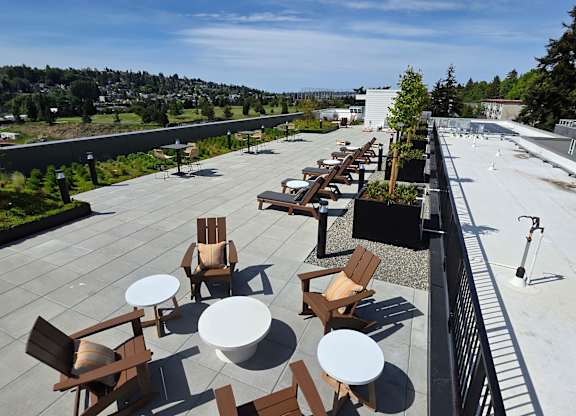 A patio with chairs and tables overlooks a city.