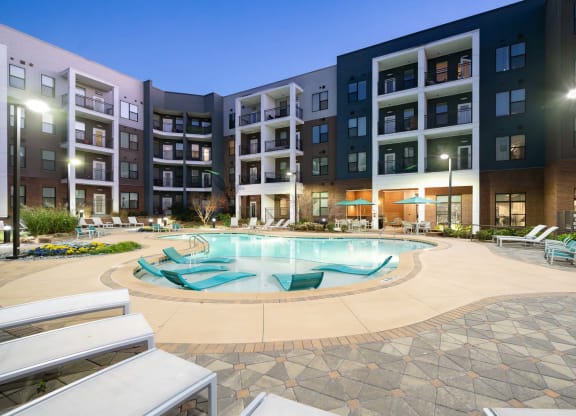 a swimming pool in front of an apartment building at night