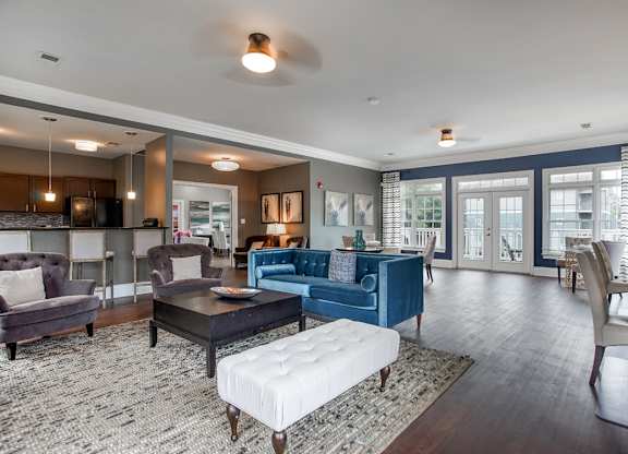 A living room with a blue couch and a white ottoman.