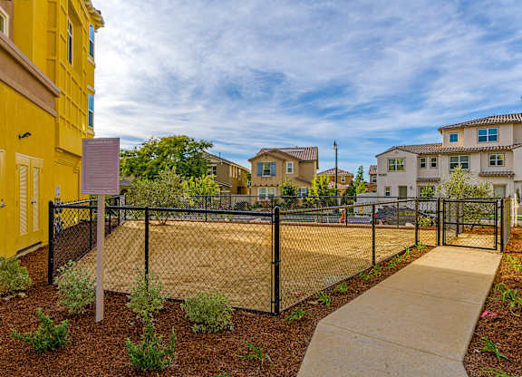 A yellow building with a black fence and a sign in front of it.