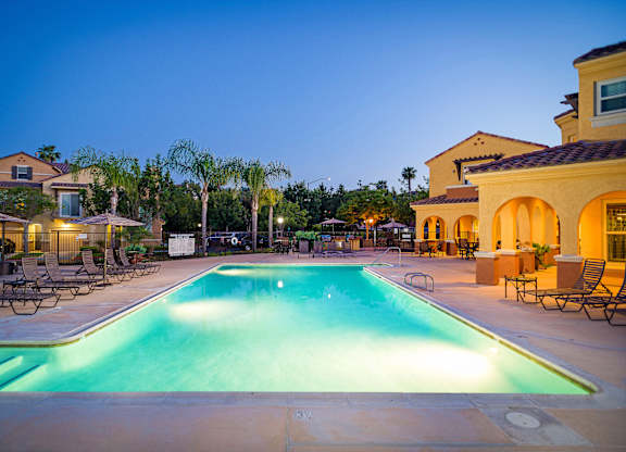 A large swimming pool surrounded by lounge chairs and palm trees.