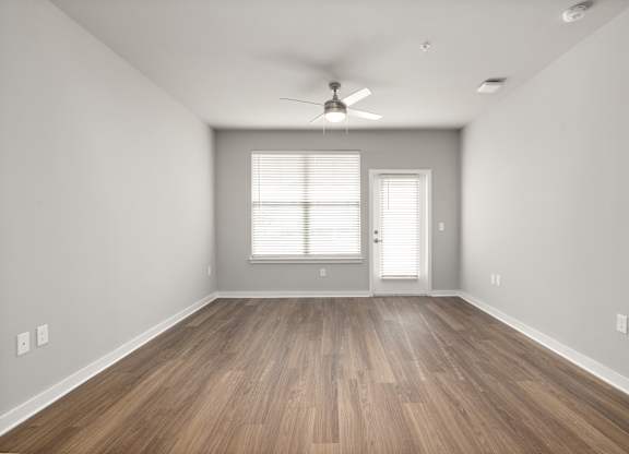 A room with a ceiling fan and wooden flooring.