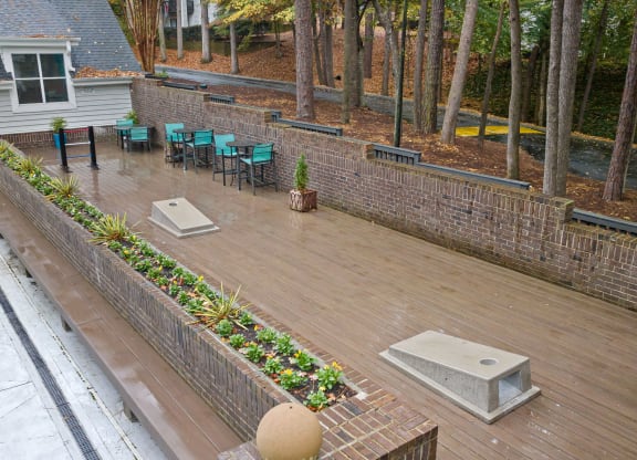 a large deck with a brick fence and a table and chairs