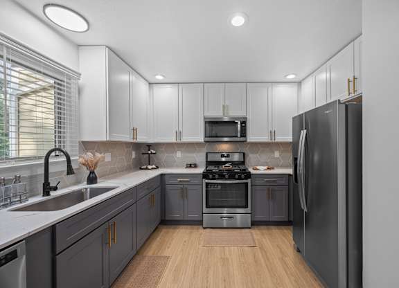 Apartments Near UNC Asheville - Verde Vista - Kitchen with Wood-Style Plank Flooring, Quartz Countertops, Two-Tone Cabinetry, Deep Sink, Range, Microwave, and Refrigerator.