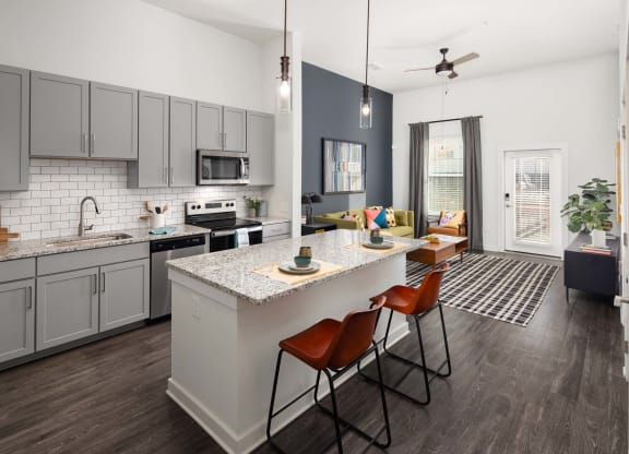 an open kitchen and living room with an island and chairs