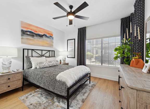 A bedroom with a bed, dresser, and ceiling fan.