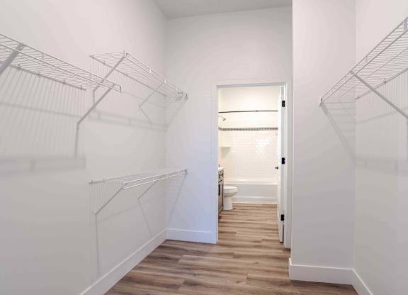 an oversized closet with white walls and wood floors