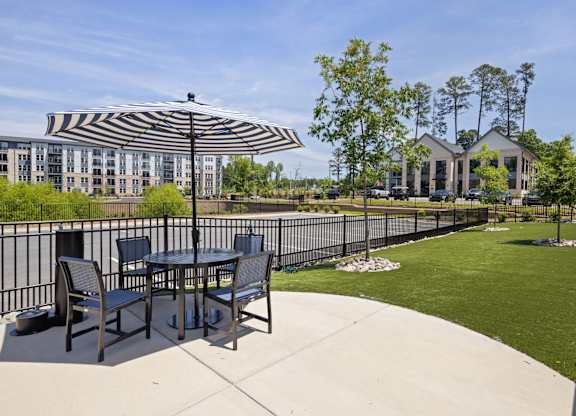 A patio with a table and chairs under a striped umbrella.