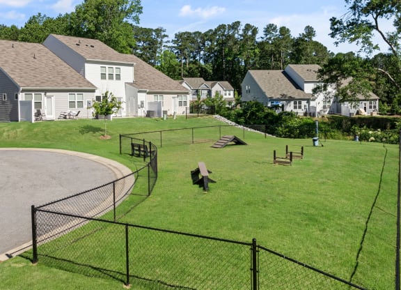 a fenced in dog park with houses in the background