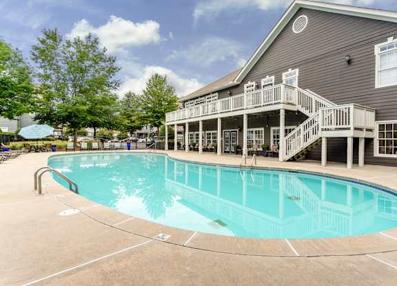 A large outdoor swimming pool with a deck and stairs leading to a building.