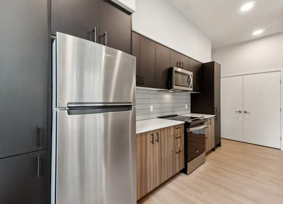 A modern kitchen with a stainless steel refrigerator and wooden cabinet at Ion Town Center, Shoreline, WA 98133.