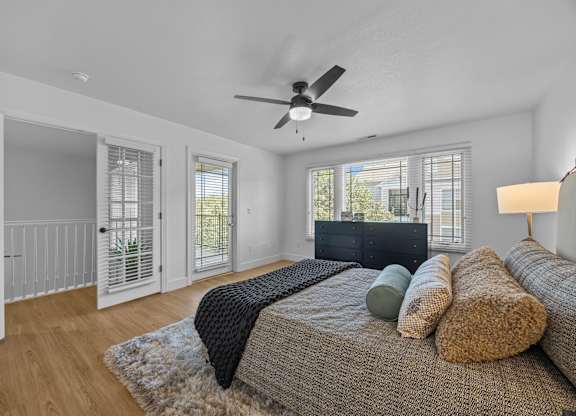 A bedroom with a bed, pillows, and a ceiling fan.